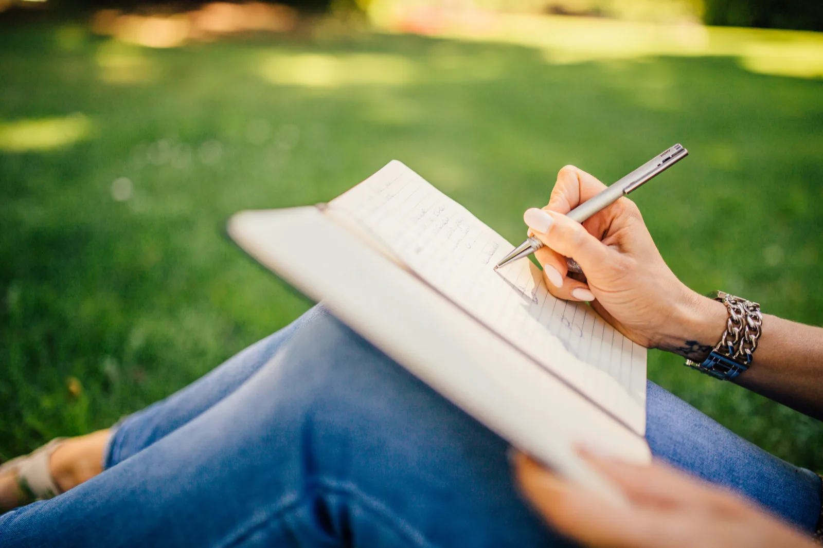Personne écrivant dans un journal sur l’herbe